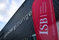 Außenansicht eines Gebäudes mit der Aufschrift ‚gonsberglounge‘ auf dunkler Fassade; im Vordergrund ein rotes ISB-Banner mit dem Text ‚ZUKUNFT. FÖRDERN. WERTE SCHAFFEN.
